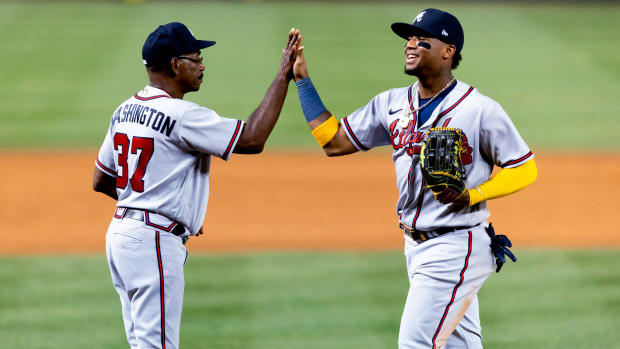 Atlanta Braves’ Ronald Acuña Jr. high-fives third base coach Ron Washington following the team’s baseball game against the Washington Nationals on Tuesday, June 14, 2022, in Washington. The Braves won 10-4.